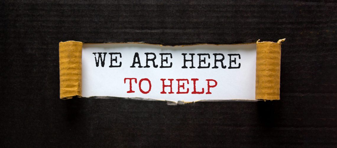 The words 'we are here to help' appearing behind torn black paper. Beautiful background. Business concept.